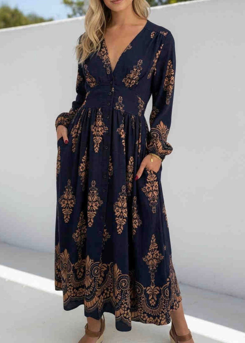 Navy blue dress with gold patterns worn by a person on a white background
