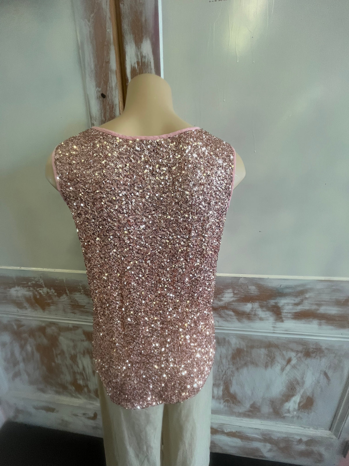 Rose gold glittery phone case on a mannequin arm against a neutral background