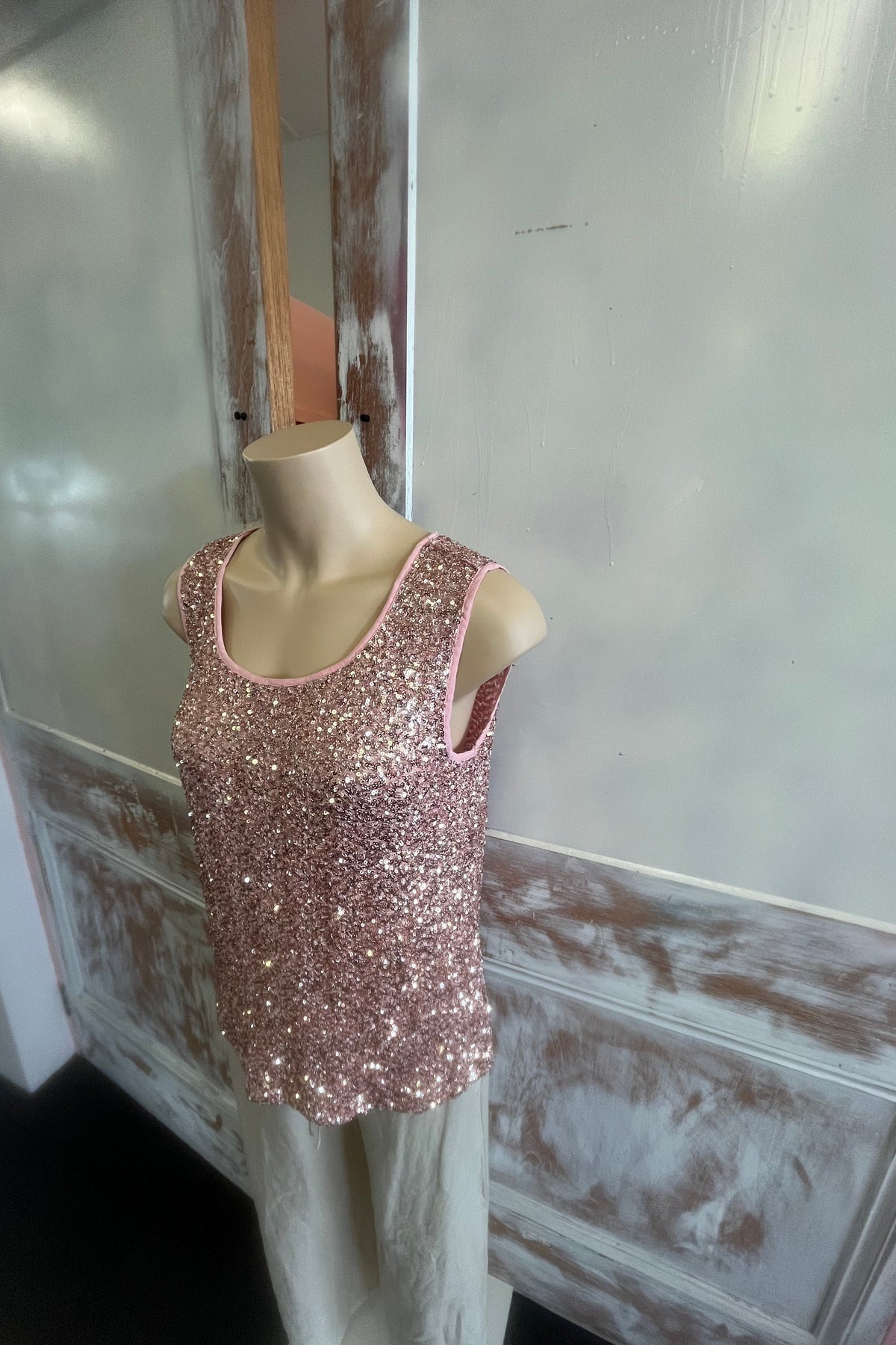 Pink glittery shoe on a mannequin foot against a neutral background