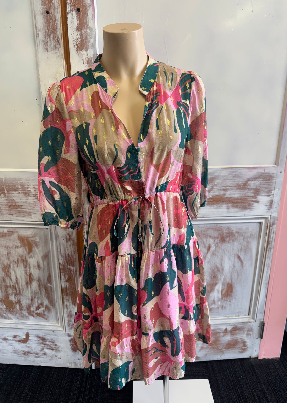 Colorful floral dress on a mannequin against a rustic wooden door background