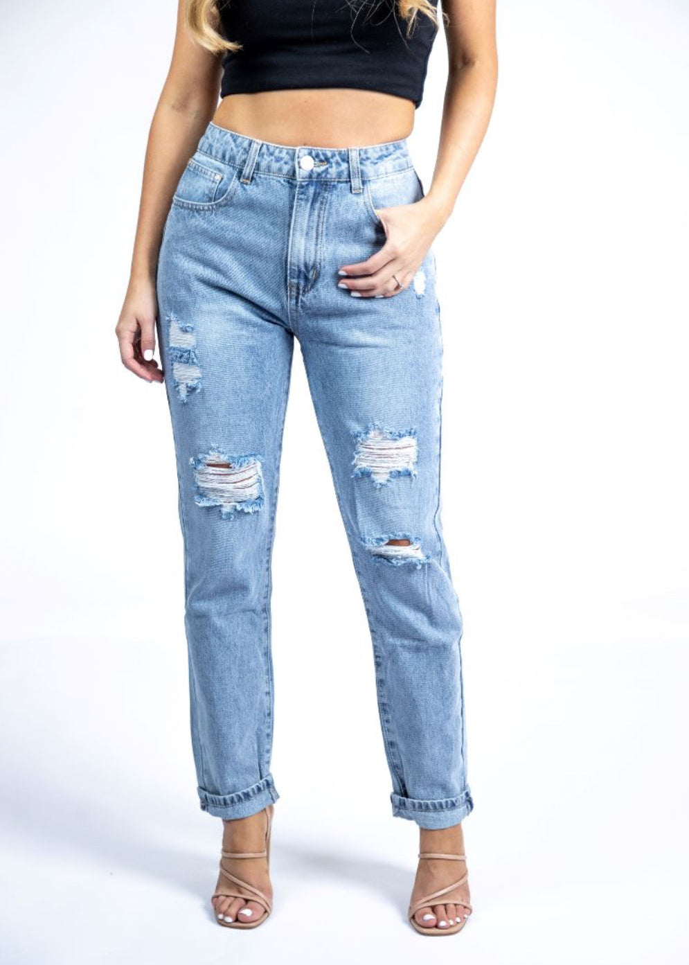 A pair of mom jeans with rips, displayed on a model standing against a white background.
