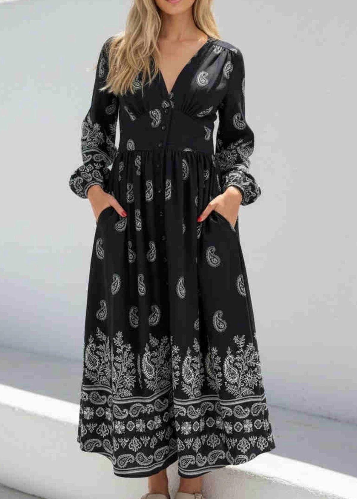 Woman wearing a black dress with white patterns against a light background