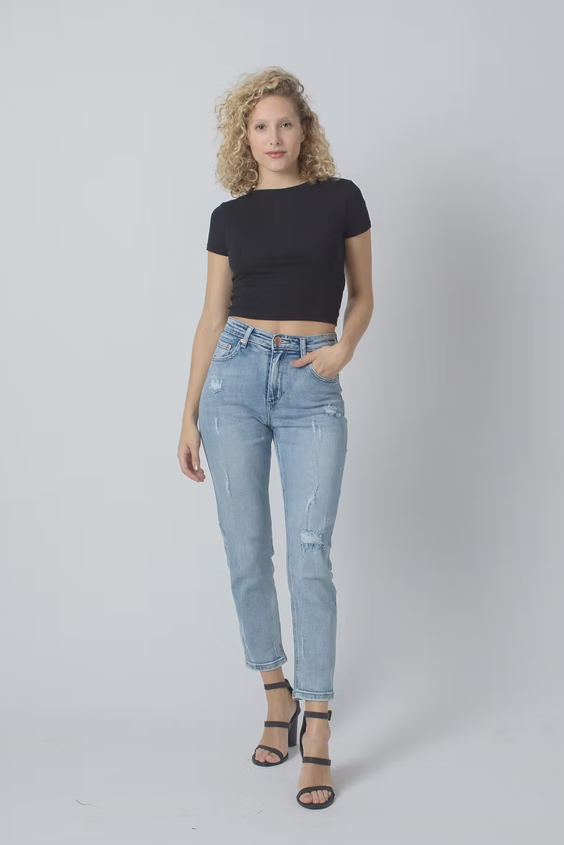 Woman wearing light blue jeans and a black top on a white background