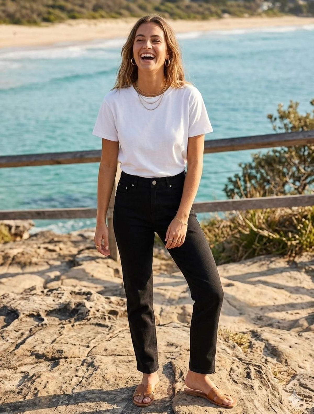 Rumours & Runways black denim straight leg Wakee Jeans worn by a woman on a rocky coastline.